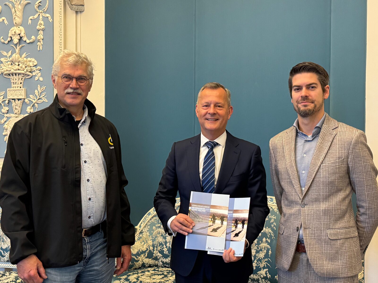 Drie mannen naast elkaar waarbij de middelste twee versies van een nieuw verschenen rapport van de Fietsersbond en Bouwend Nederland in zijn handen heeft.